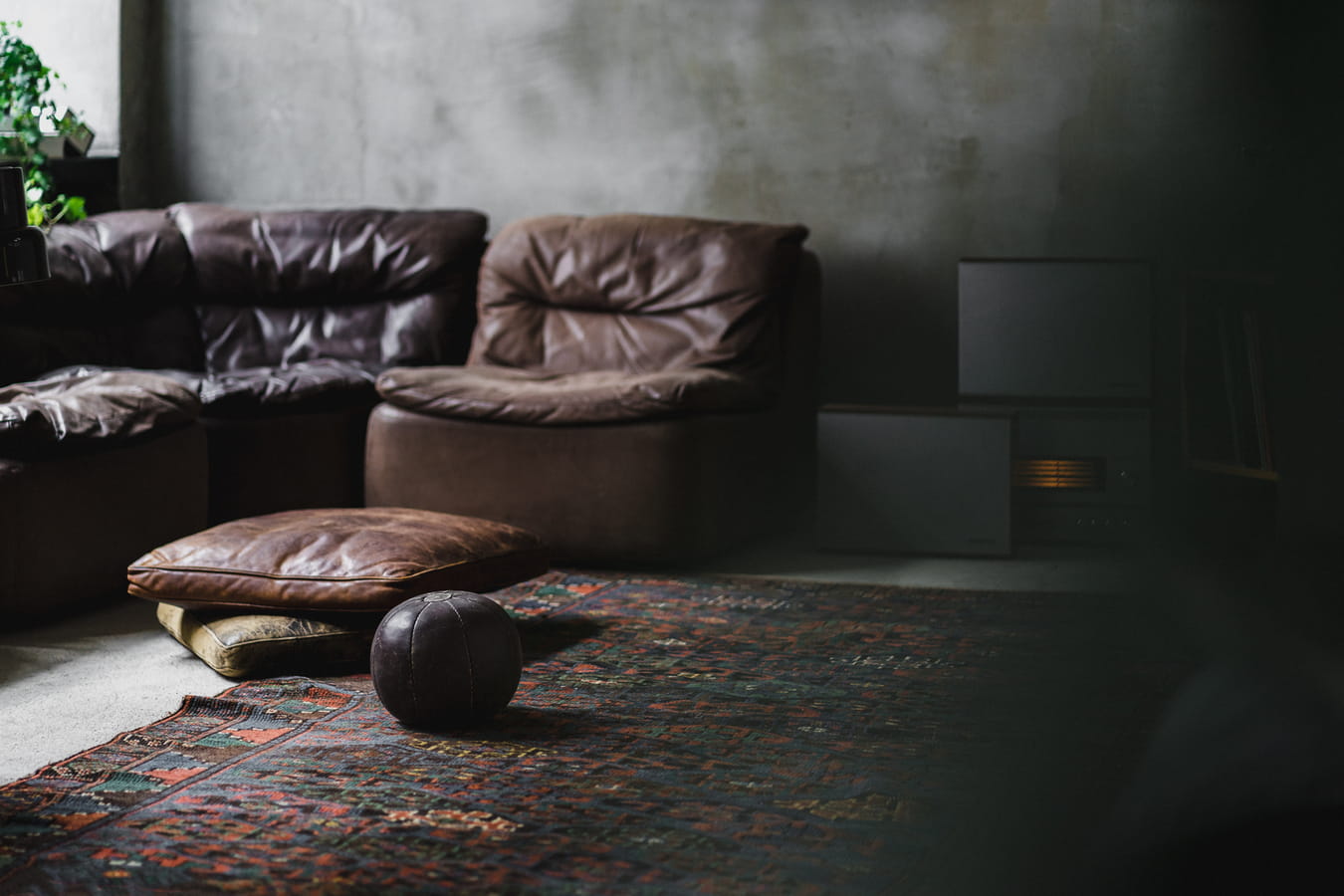 Brązowa skórzana sofa z pufą na perskim dywanie