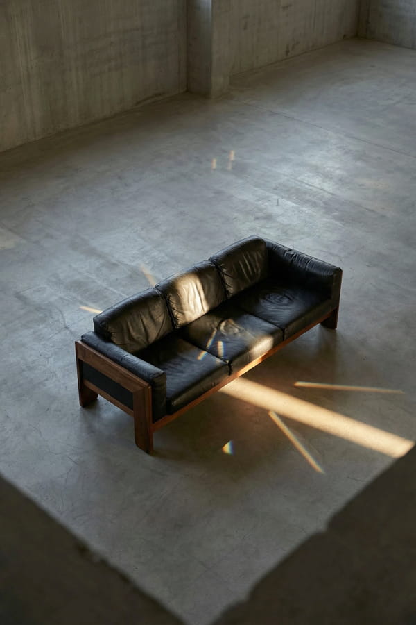 Czarna skórzana sofa z drewnianą ramą w betonowym wnętrzu